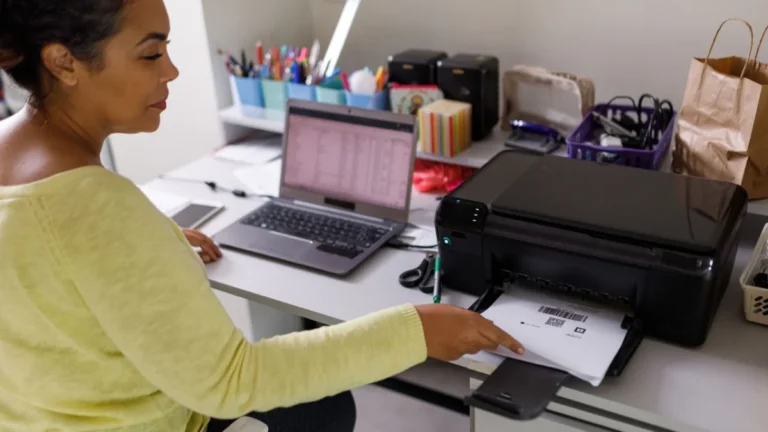 Woman sitting at desk picking identification code paper from printer