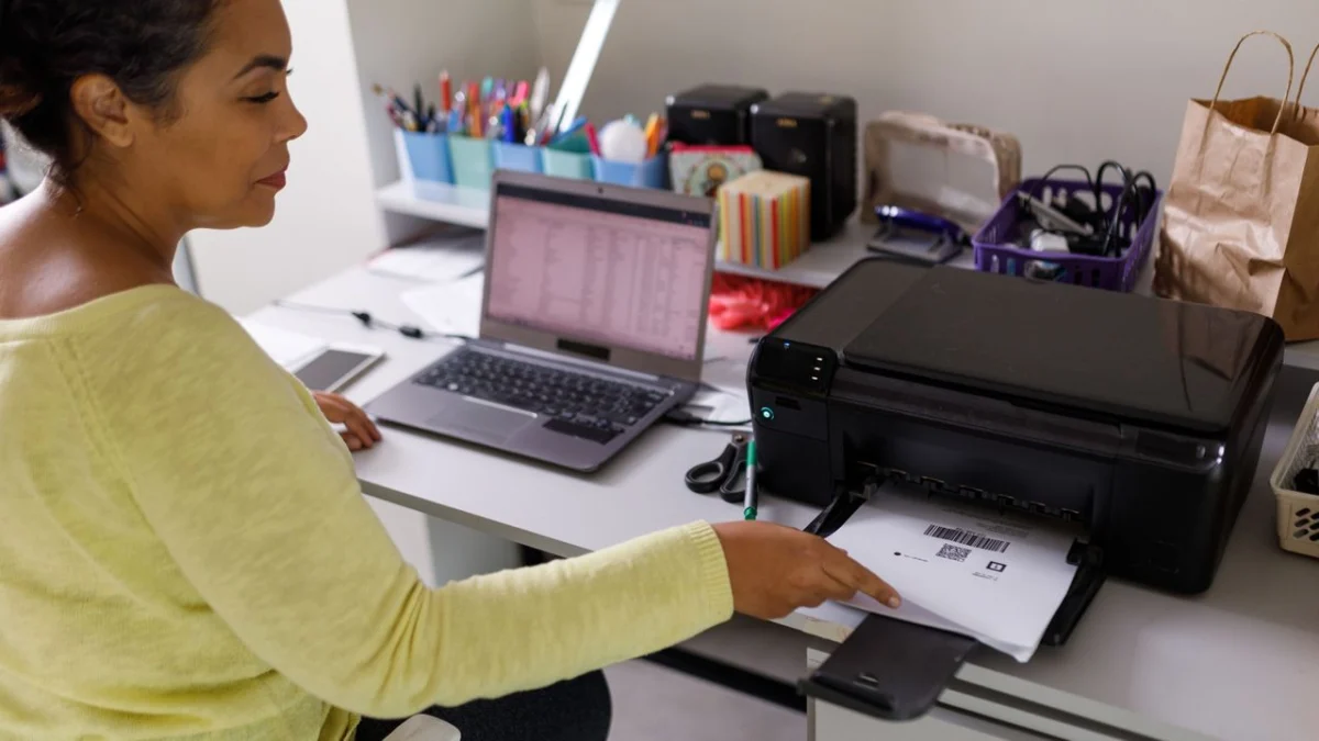 Woman sitting at desk picking identification code paper from printer
