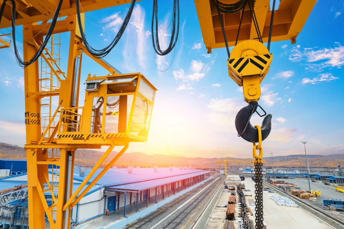 Yellow,Overhead,Crane,Unloading,Cargo,From,Freight,Cars,At,Industrial